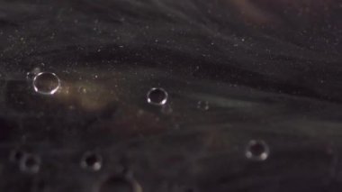 Lüks mürekkep. Parıldayan boya. Odaklanamayan siyah altın rengi yüzen şeffaf yağ kabarcıkları ışıldayan parçacıklar parıltı emülsiyon hareketi soyut sanat arka planı.