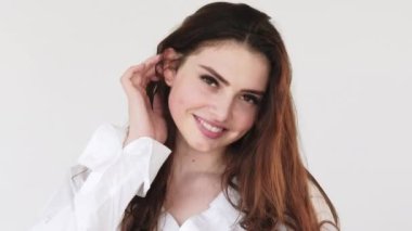 Güzel surat. Kadın güzelliği. Kendine güveni tam, flört eden mutlu, neşeli bir kadın gülümseyen, beyaz fotokopi odasında izole edilmiş saçlara dokunan..