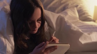Gece evde boş zaman. Çocuk alışkanlığı. Sanatsal beceriler. Düşünceli küçük bir kızdan esinlendim. Uyumadan önce çizim yapmaktan zevk alıyorum. Gece geç saatte sıcak lamba ışığıyla evde yatıyorum..