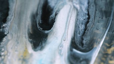 Sıvı akryl damlası. Parlak mürekkep karışımı. Odaklanmamış beyaz gri boya yağı emülsiyonu. Altın rengi soyut arkaplanda parlak parçacıklar akıyor..