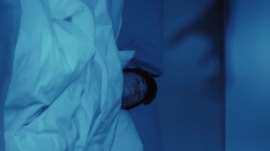 Dikey video. Gece terörü. Uyku bozukluğu. Karanlıkta duvarda canavar el gölgesi kabusundan korkmuş bir adam uyandı..
