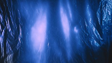 Buruşuk folyo. Buruşuk doku. Odaklanamayan parlak mavi renkli, soyut lens efektli polietilen film..