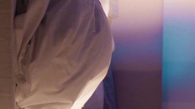 Dikey video. Gece nöbeti. Gizli online sohbet. İtaatsiz genç adam, ebeveyn kontrolünden gelen telefonla battaniyenin altında saklanıyor..