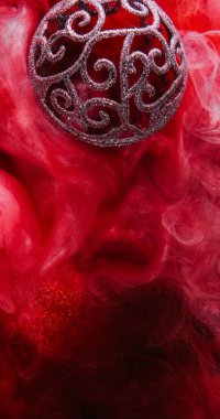 Xmas mücevheri. Renk sisi. Odaklanmamış parlak parıltılı kırmızı girdap dokusu küre yüzen mürekkep suyu akışı Noel süslemesi soyut arka plan.