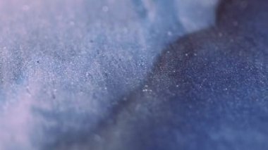 Dalga hareketi. Köpüklü sıvı. Işıldayan parlak mavi sıvı parlayan parçacıklar hipnotik soyut sanat arka planında parlak doku akışı.