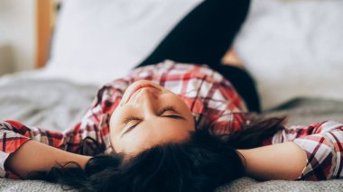 Ev istirahatı. Stres atmak. Mutlu haftasonları. Tatmin olmuş bir kadın, yumuşak yatağında uzanıyor, gözlerini kapatıyor, yatak odasını aydınlatıyor..