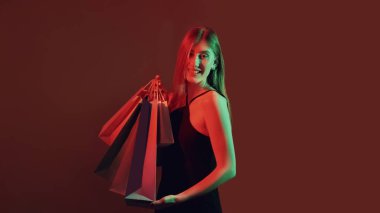 Kara Cuma. Alışveriş satışı. Tüketim sektöründe indirim. Kırmızı yeşil ışık, koyu renk fotokopi arka planında alışveriş torbaları taşıyan neşeli, neon ışıklı kız..