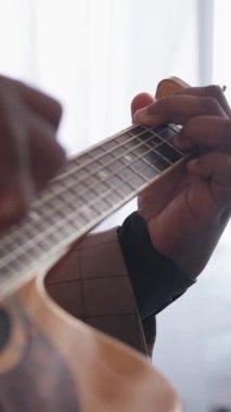 Dikey video. Gitar alıştırması. Akort çalıyor. Müzik hobisi. Yetenekli sanatçı parmaklarını içeride akustik enstrüman üzerinde şarkı söyleyen parmaklar..