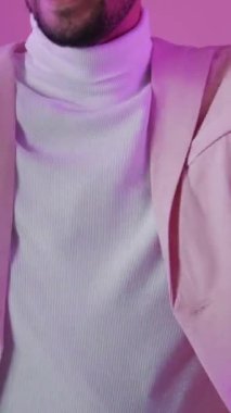 Dikey video. Disko partisi. Müzik eğlenceli. Özgürlük sevinci. Mor renkli, neon ışıklı, kendine güvenen, gözlüklü, rahat, pembe üzerinde yalnız dans eden adam..