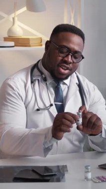 Dikey video. Aşı aşısı. Tıbbi tavsiye. Modern klinikte etkili ilaç şişesi dozunu tanıtan neşeli doktor..