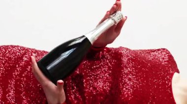 Dikey video. Parti şişesi. Tatil neşesi. Kırmızı, parlak kokteyl elbisesi içinde, beyaz bir şampanyayla dans eden tanınmayan bir kadın..