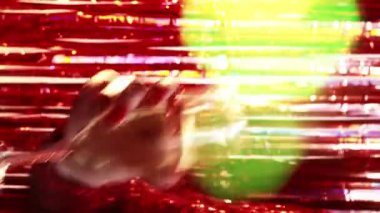 Dikey video. Parti içkisi. İyi ki doğdun Tatil kutlaması. Tanımlanamayan bir kadın bir bardak şampanyayla dans ediyor. Renkli bir mercekle, parlak kırmızı bir flaşla arka planda..