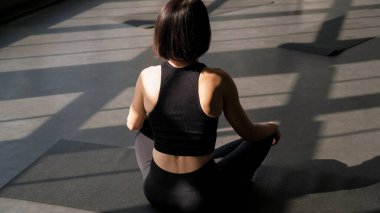 Yogaya dikkat et. Zen alıştırması. Tanınmayan bir kadın, Lotus pozu verip meditasyonun tadını çıkarıyor. Spor salonundaki spor salonunun içindeki jimnastik enerji dengesinin tadını çıkarıyor..