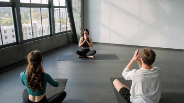 Meditasyon grubu. Yoga eğitimi. Insanlar bayan spor eğitmeni ile ders Lotus poz ile namaste jest kapalı spor salonu.