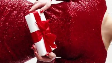 Dikey video. Noel hediyesi. İyi tatiller. Kırmızı pullu elbiseli, mutlu, tanınmayan bir kadın hediye kutlamasıyla eğleniyor..