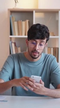 Dikey video. Gezici zafer. Haberler iyi. Terfi kutlaması. Şaşırtıcı heyecanlı adam telefonuna hayret verici bir tepkiyle cevap veriyor. Evet, modern iç mekanda bir jest..