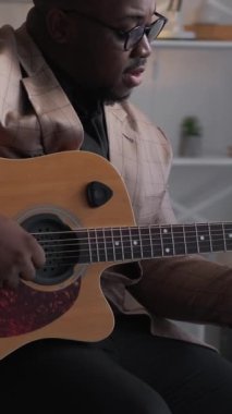 Dikey video. Gitar müziği. Sanatçı oynuyor. Şarkı söyleme alıştırması. Yetenekli bir adam akustik telden caz melodisini öğreniyor..