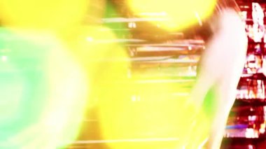 Dikey video. Noel büyüsü. Yeni yıl partisi. Tatil kutlaması. Renkli lenslerle dans eden kadın elleri ışıl ışıl parıldayan kırmızı süslemeler üzerinde.