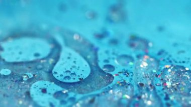 Renk mürekkebi dökülmüş. Parlak yağ kabarcıkları. Odaklanmamış mavi ışıldayan parçacıklar jel damlaları akrilik boya sıvısı parlatıcı doku akış hareketi soyut sanat arka planı.