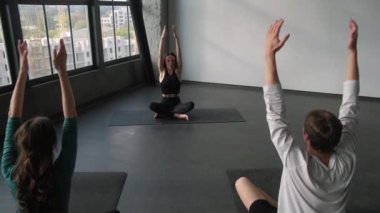 Yoga insanları. Fitness seansı. Nilüfer pozisyonunda oturan kadın spor eğitmenli aktif bir grup. Antrenman, amaste jesti, kapalı spor salonundaki sarılma..