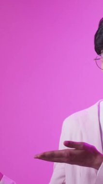 Dikey video. Tavsiye edilen insanlar. Mükemmel seçim. Mor renkli neon ışık tatmin edici adam pembe boş alan reklam arka planında onay başparmağını gösteriyor..
