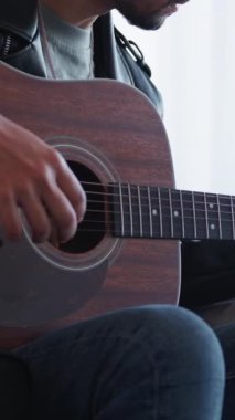 Dikey video. Gitar hobisi. Müzik çalıyor. Yaratıcı yetenek. Rock haftasonu. Tanınamayan ilham verici adam akustik enstrüman tellerini ayarlıyor sesi kontrol ediyor.