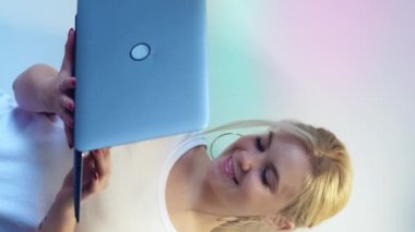 Dikey video. Laptop tipi. İyi sohbetler. Sosyal medya. Neşeli kız internette geziniyor. Yumuşak gökkuşağı eğiminde tarayıcı uzaktan mesajı kullanıyor..