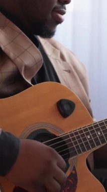 Dikey video. Gitar sanatçısı. Müzik alıştırması. Tanımlanamayan yetenekli erkek elleri telli çalgılarla şarkı akorları çalıyor içeride yaratıcı aktivitelerden keyif alıyor..