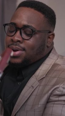 Dikey video. Erkek müzisyen. Gitar şarkısı. Yaratıcı hobi. Neşeli, ilham verici, telli enstrümanla melodi çalan adam evde sesin keyfini çıkarıyor..