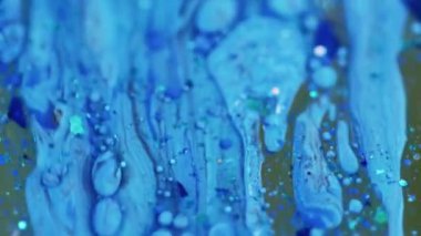 Akrilik sıvı damlası. Parıltılı boya döküldü. Odaklanmamış mavi renkli parlak pullu partiküller parlaklığı desen su emülsiyon sıvı mürekkep akışı hareket soyut sanat arka planı.