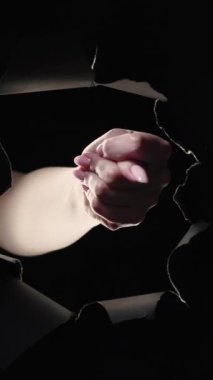 Dikey video. İncir işareti. Dolandırıcılık. Reddedilmiş bir kadın eli. Siyah delikte hiç hareket yok. Karanlık gece fotokopi arka plan döngüsünde yırtılmış duvar..