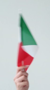 Dikey video. İtalya bayrağı. Ulusal sembol. Tarafsız arkaplanda yeşil beyaz, üç dikey çizgili İtalyan el sallayan bir kadın..