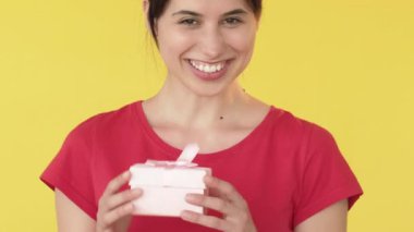 Beklenmedik bir hediye. Kadın hediye alıyor. Rüya tatmini. Mutlu bir mutluluk. Sarı arka planda izole edilmiş bir kutu..