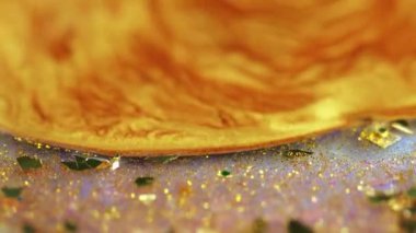 Sıvı altın. Parıldayan sıvı dökülmüş. Odaklanamayan sarı renk parıldayan metalik pullu parçacıklar akrilik boya mürekkebi akrilik hareketli soyut sanat arkaplanı ve bokeh ışıkları.