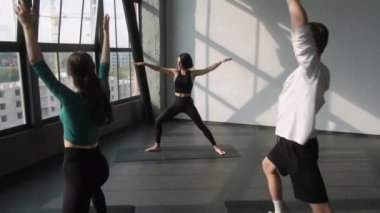 Yoga eğitmeni. Spor salonu. Atletik bayan spor antrenörü aktivite kıyafetleri grubunda insanlar denge egzersizi yapıyor. Asana pozu, kapalı spor salonunda vücut duruşu, kapalı spor salonunda..
