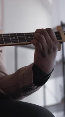 Dikey video. Gitar şarkıcısı. Müzikal hobi. Şarkı eğlencesi. Telli akustik enstrüman çalan neşeli yetenekli adam evde ses egzersizi yapıyor..