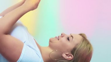 Dikey video. Mesaj yazıyorum. Akıllı telefon sohbeti. Neşeli canlı kadın sosyal medyadan zevk alıyor gökkuşağı rengi gradyan boş alan arkaplanı.