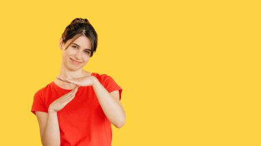 Kes jesti. Zaman doldu. Kırmızılı, kuşkucu, gülümseyen kadın sarı boş arkaplanda ayrık işareti gösteriyor..