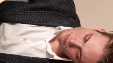 Dikey video. İş görüşü. Düşünceli adam. Endişeli yakışıklı adam modern takım elbise içinde oturmuş geleceğin başarısını hayal ediyor. Yeni fikirler yazıyor..