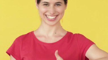 Destek jesti. Neşeli kadın. Onaylanan başparmaklar, gülümseyen mutlu, kendine güvenen çantalar sarı boş alanda izole edilir..