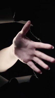 Dikey video. Şöyle böyle bir jest. Anlamsız cevap. Kafa karışıklığı şüphesi. Kara deliğin içinde el sallayan kadın kara gece arkaplan döngüsünde duvarı yırttı.