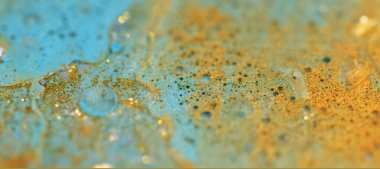 Altın parçacıklar. Köpüklü sıvı doku. Bulanık mavi renk parlak metalik pullu akrilik sıvı mürekkep akışı soyut sanat arka planında bokeh ışıkları.