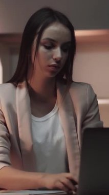 Dikey video. İşi bitirdim. Kendi başına çalışıyor. Yoğunlaşmış ofis işkadını bilgisayarını kapatıp karanlık işyerini terk ediyor..