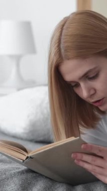 Dikey video. Edebiyat molası. Ödev çalışması. Genç, ciddi, kendinden emin, okumayı öğrenen bir kız öğrencinin kitap kapama işini bırakması..