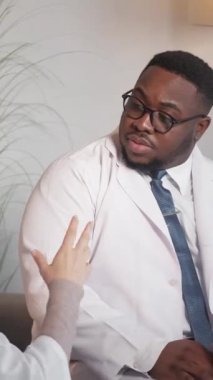 Dikey video. Tıp arkadaşları. Kahve molası. Sağlık hizmetleri tartışması. Profesyonel erkek ve kadın doktorlar klinikte çay içerken teşhis hakkında konuşuyorlar..