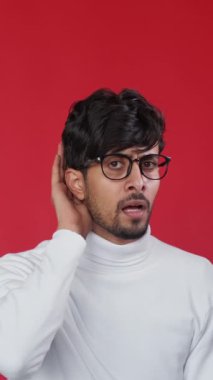 Dikey video. Dedikodu şoku. Gizli sürpriz. Kırmızı fotokopi arkaplanından izole edilmiş garip, sersemlemiş bir adam kulak misafiri..