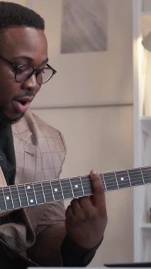 Dikey video. Müzik okulu. Gitar öğretmeni. Erkek profesyonel sanatçı, içerideki sınıflarda telli çalgı dersini açıklıyor..