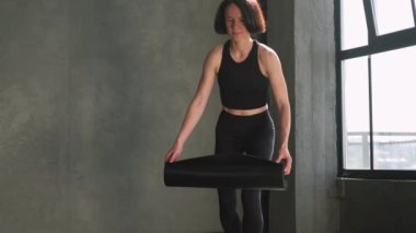 Pilates eğitimi. Fitness egzersizi. Spor elbiseli atletik bir kadın spor salonundaki spor salonunda egzersiz yapmadan önce yerde yoga minderi açıyor..