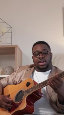 Dikey video. Müzik blogcusu. Gitar kursu. Uzaktan eğitim. Evdeki sanal toplantıda enstrüman dersi veren adam akorları açıklıyor..