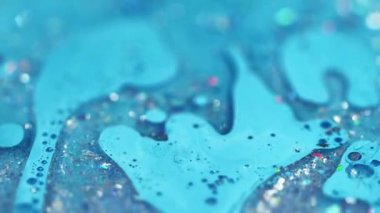 Parıltılı bir karışım. Akrilik boya dökülmüş. Odaklanmamış mavi renk parlak pullu parçacıklar jel sıvısı yüzen kabarcıklar mürekkep emülsiyon sıvı akım hareket soyut sanat arka planı.